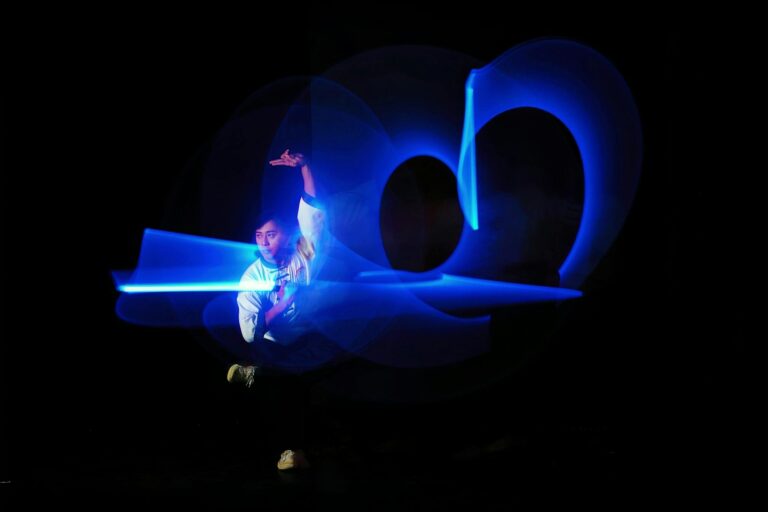 A captivating dance performance with blue light trails creating artistic shapes against a dark background.
